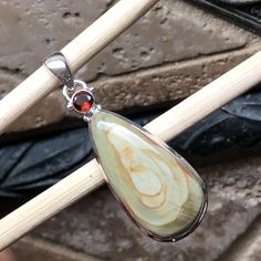 a wooden stick with a stone pendant on it's end and a red bead hanging from the end