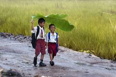 two young boys walking down a dirt road next to tall green grass and the words neu co th duoc quay lai