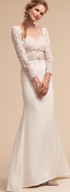 a woman in a white wedding dress with long sleeves and lace on the top, posing for