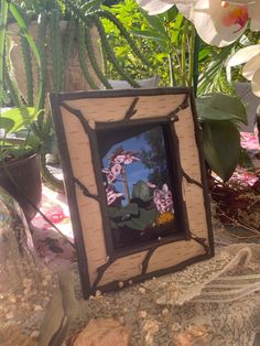 a photo frame sitting on top of a table next to potted plants and flowers