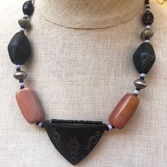 Vintage African wood necklace. Nice handcrafted silver scroll work. Most likely from Ghana but this piece was bought vintage. Large carnelian gemstones. Hook clasp Size - Main triangle is 2 x 1.5 inches, chain is 20 inches long  Material - Wood, beads, metal, carnelian Condition - Good. Some wear and age but contributes to look. See close ups Vintage Brown Carnelian Necklace, Vintage Brown Agate Necklace, Brown Vintage Agate Necklace, Handmade Black Carnelian Necklace, Artisan Carved Amber Necklace, African Necklace, Scroll Work, Carnelian Beads, Wood Necklace