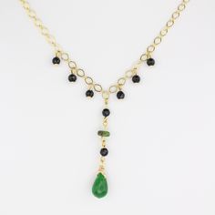 This handcrafted gemstone necklace features a stunning arrangement of one green Jade gemstone, eight Black Onyx gemstones, and one Serpentinite gemstone, all beautifully dangling from a 24K gold-filled chain. Measuring 20" long, the chain can easily be shortened to your desired length, while the Jade teardrop pendant adds an elegant 2" drop. Jade is believed to boost luck, bring relaxation, and harmonize relationships; Serpentinite is believed to build confidence, boost positivity, and balance e Gold Onyx Necklace With Adjustable Chain, Elegant 14k Gold-filled Necklaces With Natural Stones, Gold Onyx Gemstone Necklace, Elegant Onyx Wire Wrapped Necklace, Gold Onyx Necklaces With Natural Stones, Elegant 14k Gold-filled Gemstone Beads Necklace, Elegant 14k Gold Filled Gemstone Beads Necklace, Handmade Gold Onyx Necklaces, Serpentine Stone