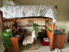 a loft bed with a desk underneath it and some plants on the bottom shelf next to it