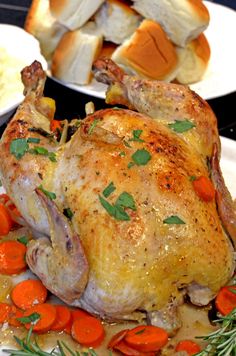 a whole chicken on a plate with carrots and bread