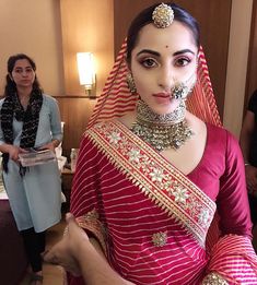 a woman in a red sari with jewelry on her neck and headpieces