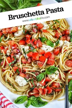 pasta with tomatoes, basil and mozzarella on a white plate next to silverware