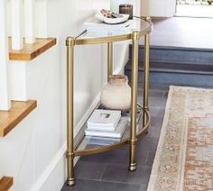 a table with a vase on it in front of some stairs and a carpeted floor