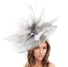 Hats By Cressida Kentucky Derby & Ascot Fascinator Hats Grey Metallic Silver Velidhoo Fascinator Hat Gorgeous long grey coque feathers on a layered metallic silver sinamay base.  Base measures about 12-14 inches wide Mounted with a matching headband. If you prefer a headband to match your hair, please make a note at check out what colour headband you want. Get ready to turn heads with the Velidhoo Fascinator Hat at your next fancy event! Perfect as a Kentucky Derby fascinator, Royal Ascot fascinator hat, or women's formal hat, this headpiece is all about elegance and sophistication. With long feathers, a sinamay base, and a unique design, you're sure to stand out from the crowd. Wear it to weddings, derby races, parties, church, or ladies day events and feel confident and stylish all day l Elegant Wedding Top Hat With Feathers, Elegant Feathered Spring Headpieces, Elegant Silver Mini Hat For Summer, Feathered Fascinator For Garden Party, Elegant Summer Feathered Headpiece, Elegant Feathered Headpieces For Summer, Elegant Summer Headpieces With Feathers, Elegant Feather Headpiece For Garden Party, Silver Wedding Fascinator For Summer