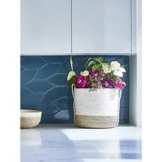 a basket filled with flowers sitting on top of a counter next to a blue tiled wall