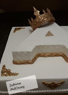 a white cake with gold decorations and a crown on top