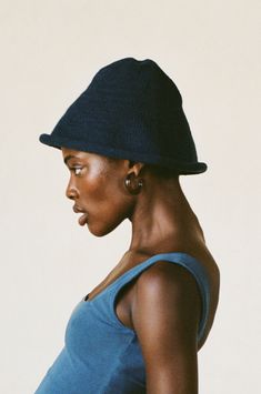 a woman wearing a blue tank top with a black hat on it's head