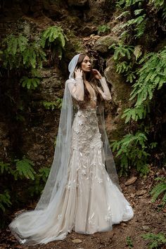 a woman in a wedding dress and veil posing for the camera with her hands behind her head