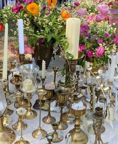 a table topped with lots of different types of candles and vases filled with flowers