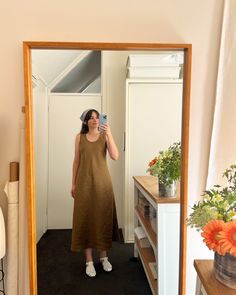 a woman taking a selfie in front of a mirror with flowers on the floor