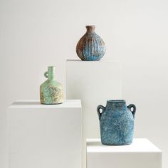 three vases sitting on top of white blocks