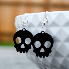 pair of black skull earrings sitting on top of a white bowl