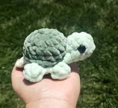 a small stuffed turtle is held in someone's hand