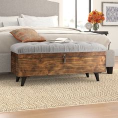 a bed with a wooden foot board and blue upholstered bench in front of it