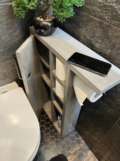 a white toilet sitting next to a wooden cabinet with plants on it's sides