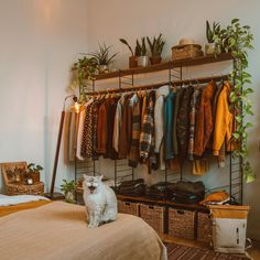 a white dog sitting on top of a bed next to a rack filled with clothes