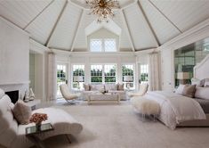 a large bedroom with white walls and furniture in the center, along with a chandelier hanging from the ceiling