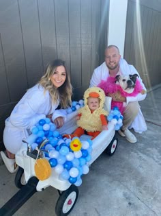 two adults and a baby in a wagon with balloons