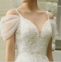 a mannequin wearing a white wedding dress with sheer sleeves and an open shoulder