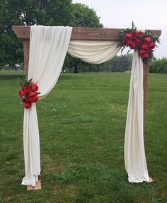 an outdoor wedding setup with red flowers and draping