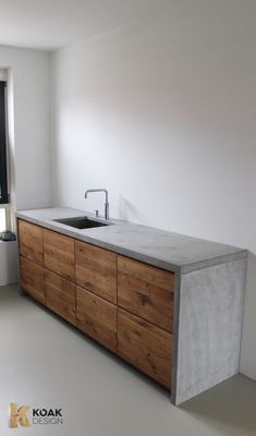 a kitchen with a sink and counter top in the middle of an empty room next to a window