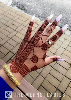 the hand with henna on it is decorated with white and gold decorations, which are accented with jewels