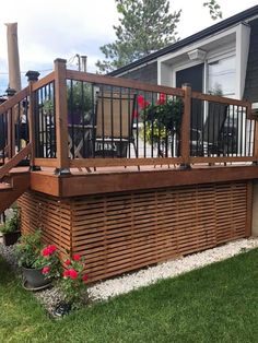 a deck built into the side of a house with potted plants and flowers on it