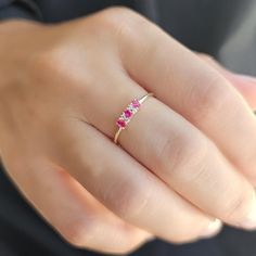 a woman's hand with a gold ring and three pink sapphires on it