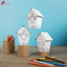 three bird houses are sitting next to colored pencils