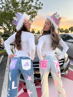 two girls in matching outfits standing next to a car with their hands on their hips