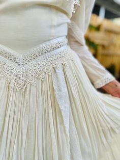 the back of a woman's white dress with lace trimmings and buttons