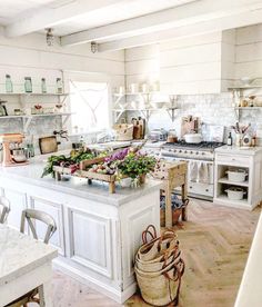 a large kitchen with white cabinets and wooden floors is pictured in this image, there are baskets on the counter