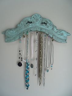 a blue wall mounted jewelry rack with many necklaces hanging from it's sides