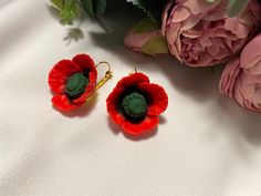 two red flowers sitting next to each other on top of a white surface with pink flowers