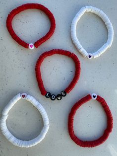 four red and white bracelets with the word love written on them are laid out