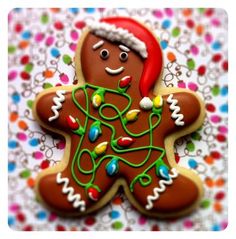 a decorated gingerbread with christmas lights on it's face and arms, sitting on a tablecloth