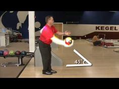 a man standing in front of a bowling ball on top of a hard wood floor