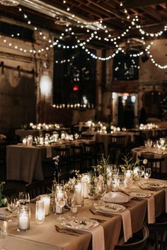 the tables are set with candles and place settings for an elegant dinner or reception at night