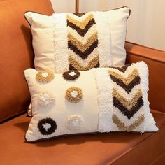 two decorative pillows sitting on top of a couch