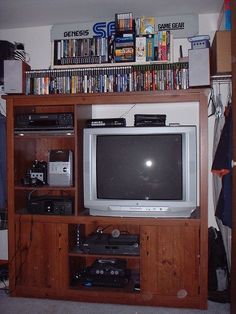 a television is sitting on top of a wooden entertainment center with several movies and video games