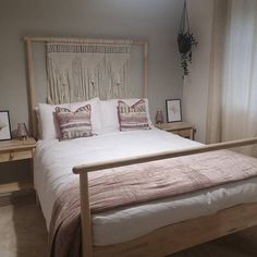 a bed with white sheets and pink pillows in a bedroom next to two nightstands