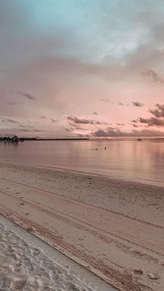 an empty beach at sunset with boats in the water