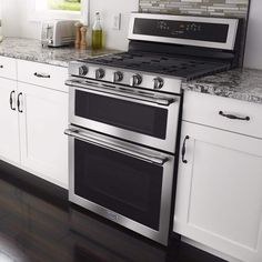 a kitchen with white cabinets and stainless steel stove top oven in the center of the room