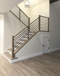 an empty living room with stairs and hard wood flooring on the side of the wall