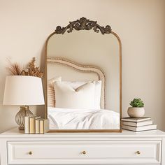 a white dresser topped with a mirror next to a lamp