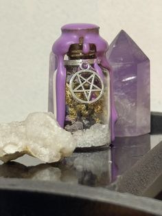 a purple glass jar with a pentagramil inside sitting on a table next to crystals